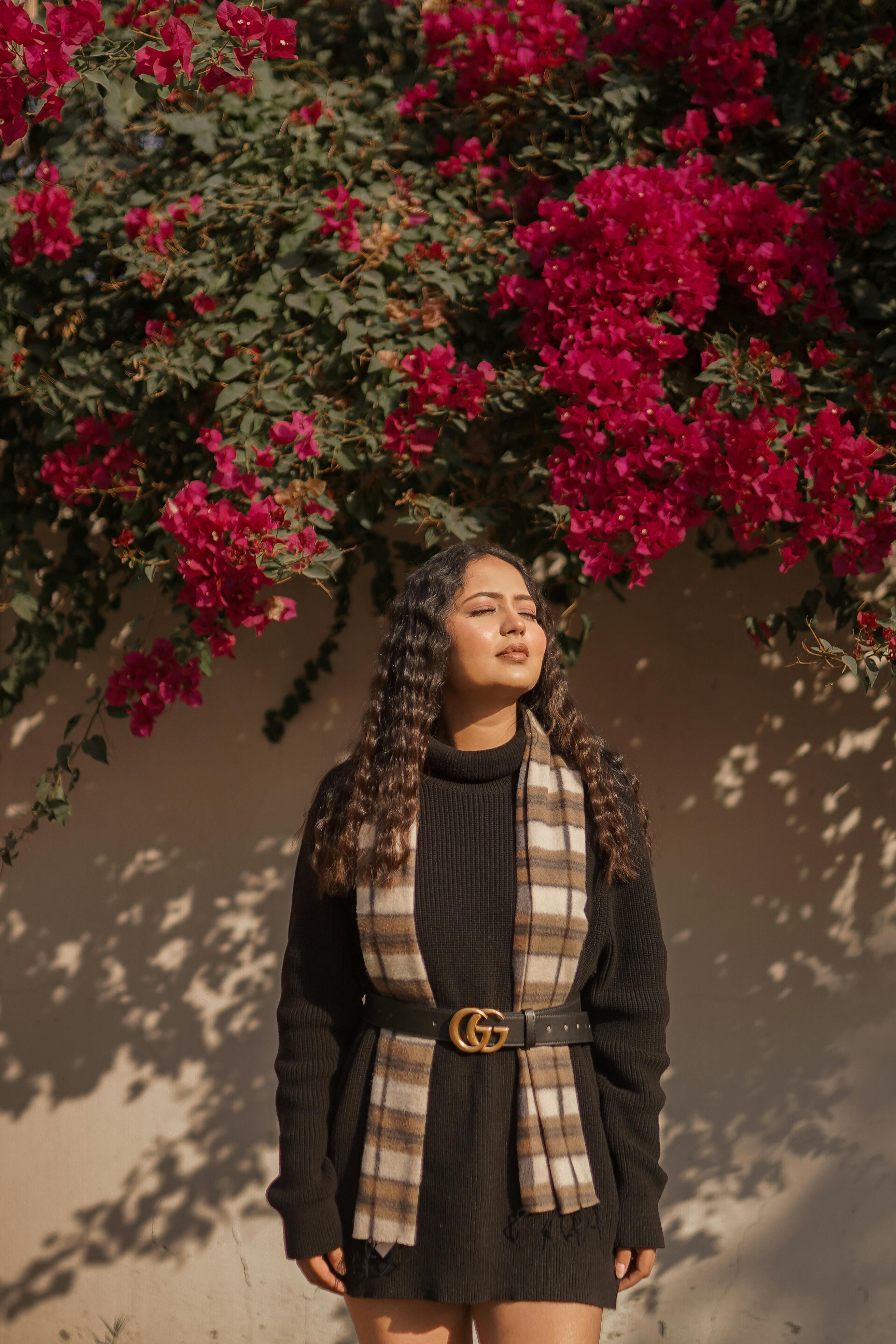 Woman standing in front of a wall with pink flowers
